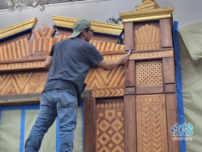 Restorer cleaning the diamond and chevron marquetry pilasters of the original Aron Kodesh at 770 Eastern Parkway, October 2023