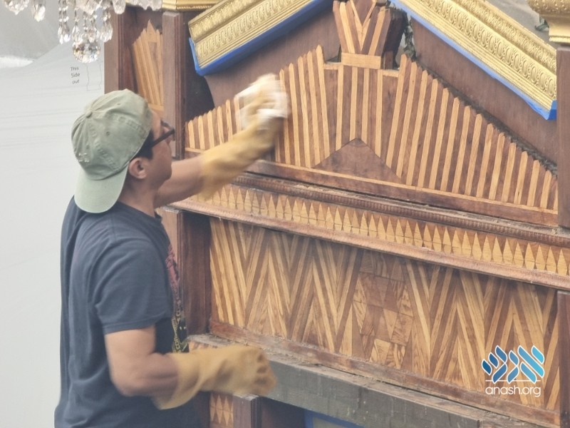 Restorer cleaning the gilded cresting and sunburst pediment of the original Aron Kodesh at 770 Eastern Parkway, October 2023