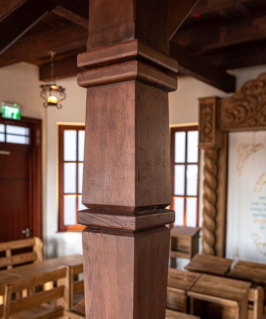 Close-up detail of a restored wooden column base at the bimah