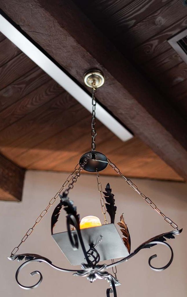 Restored wrought-iron chandelier hanging from the ceiling beams